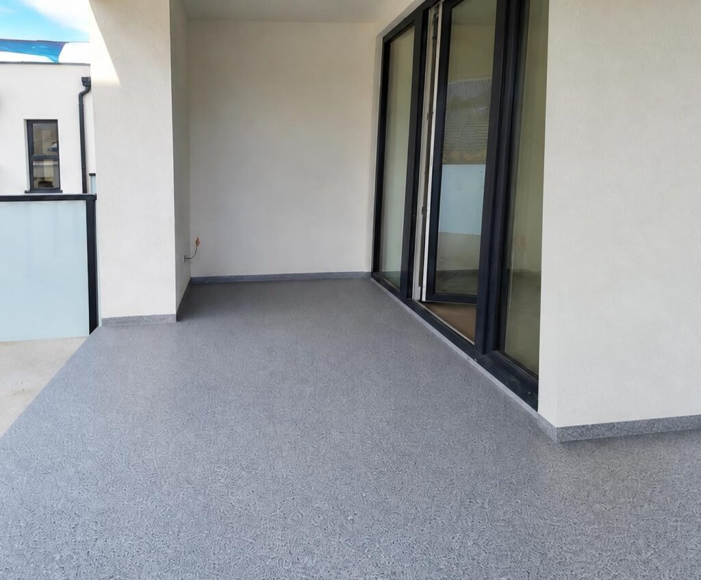 Wykończony balkon z szarą powierzchnią i przeszkleniami